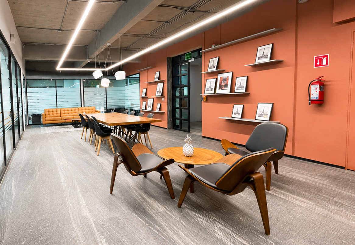 Sala de juntas Colony con mesa larga de madera, sofás y muro color terracota