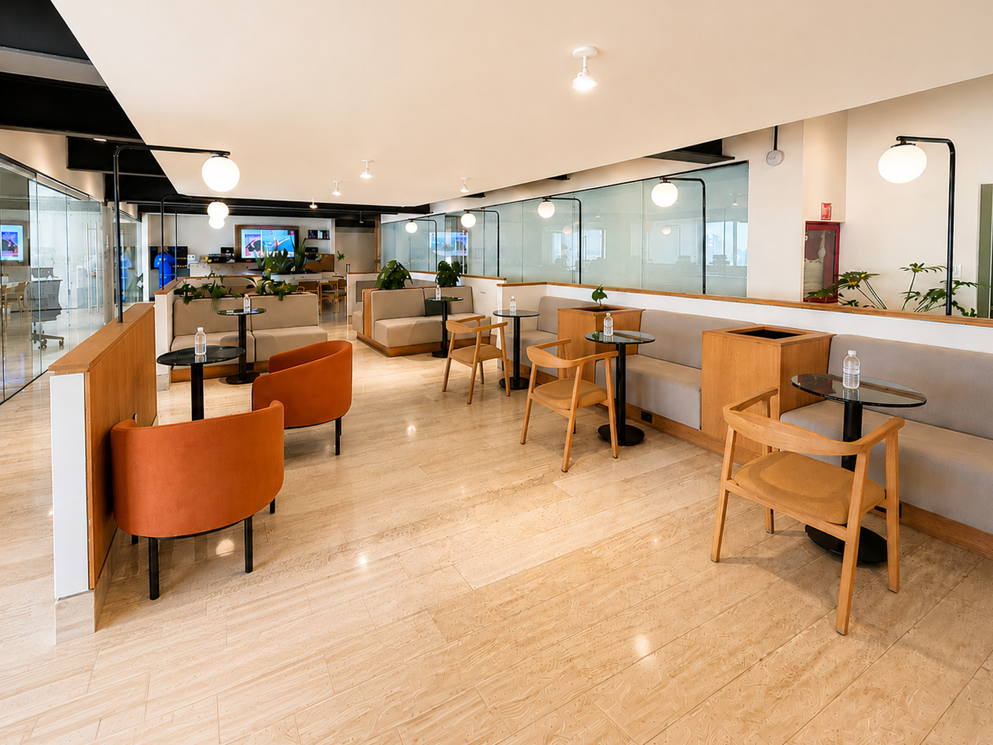 Zona de trabajo abierta de Colony con sillones, mesas pequeñas y acabados cálidos